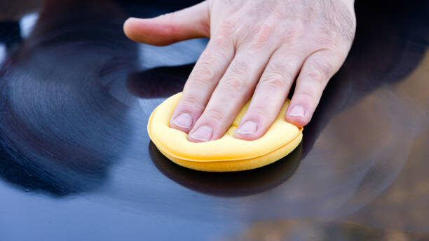 Handmatig polijsten van autolak met een applicator pad voor een glanzende en krasvrije afwerking.