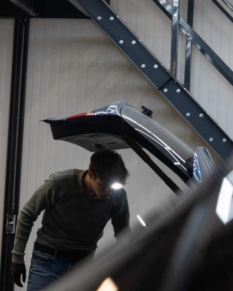 Autodetailing specialist inspecteert de kofferbak met een hoofdlamp voor een grondige reiniging en afwerking bij Jame Detail.